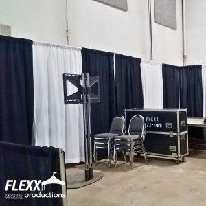 Black and white pipe and drape rentals hiding an area holding equipment at an event